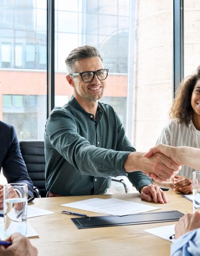 Happy businessman and businesswoman shaking hands at group meeting. Happy businessman and businesswoman shaking hands at group board meeting. Professional business executive leaders making handshake agreement successful company trade partnership handshake concept.